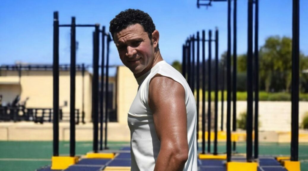 Man posing after a workout at an outdoor gym.
